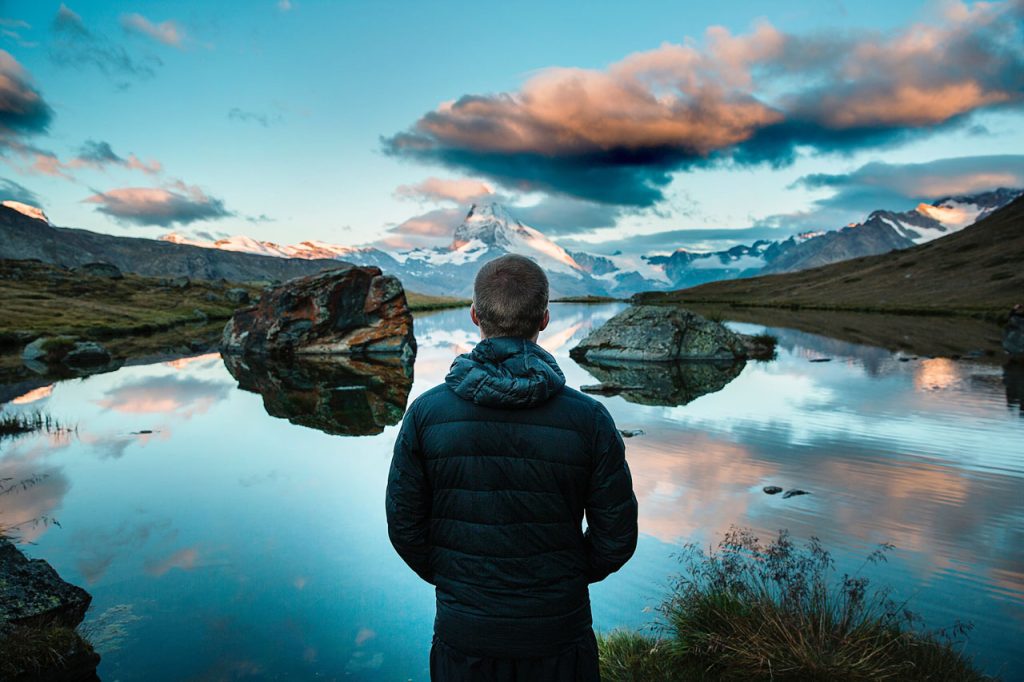 Man at edge of scenic mountain lake