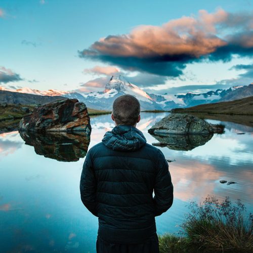 Man at edge of scenic mountain lake